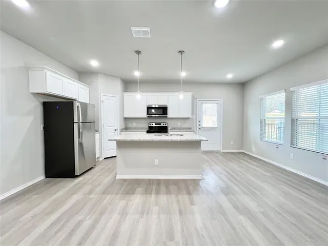a view of kitchen with stainless steel appliances kitchen island wooden cabinets and granite counter tops