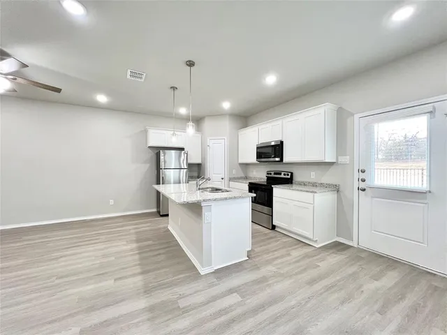 a kitchen with granite countertop a sink cabinets and wooden floor