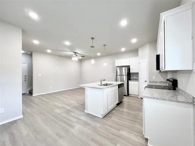 a large kitchen with granite countertop a large counter top a sink stainless steel appliances and cabinets