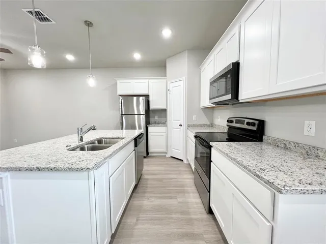a kitchen with stainless steel appliances granite countertop a sink a stove and cabinets
