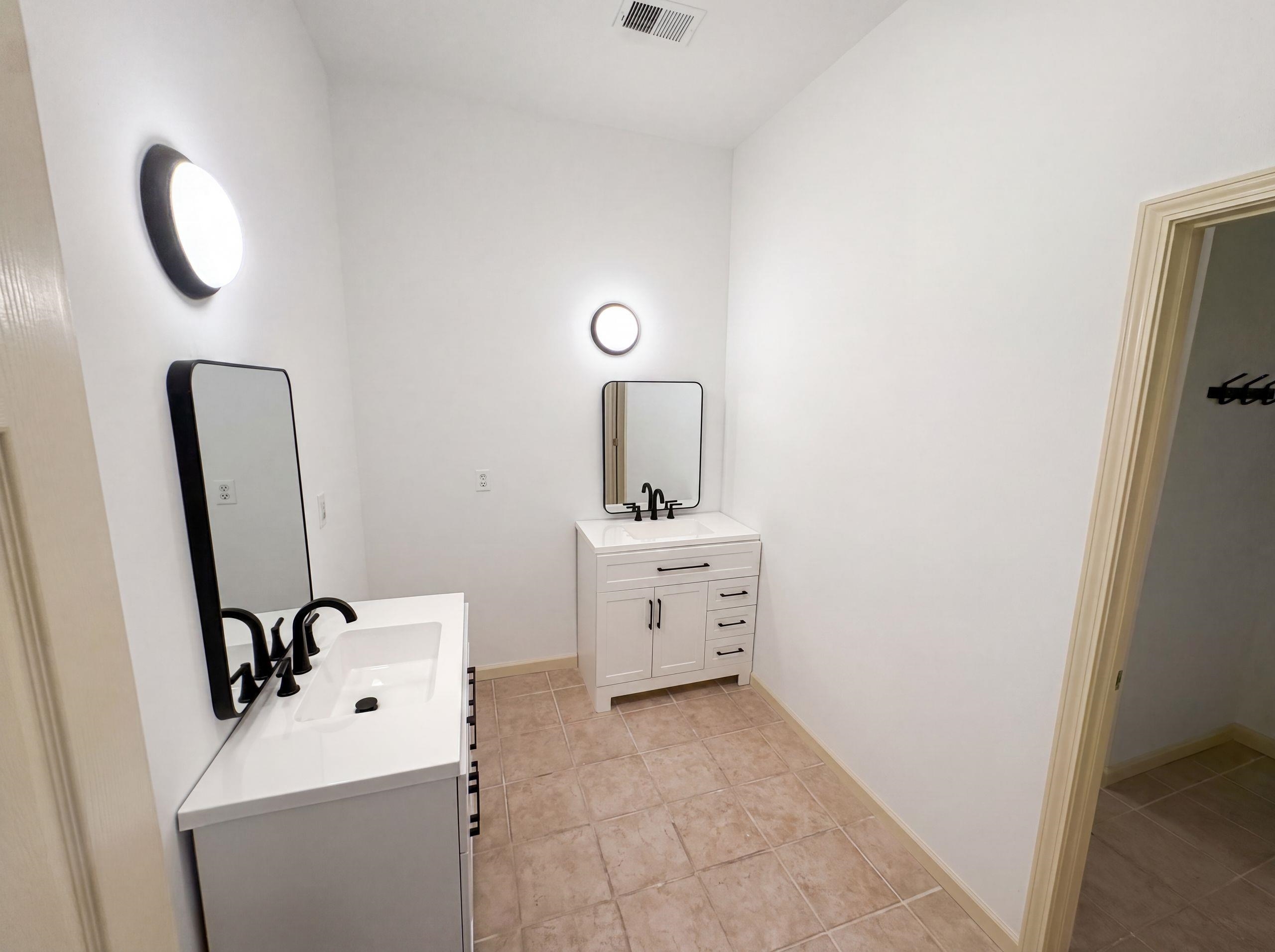 9424 Gotten Road Germantown, TN 38139 - Photo 18 of 27 Dual white vanities with integrated sinks, each featuring a matte black faucet and framed mirror