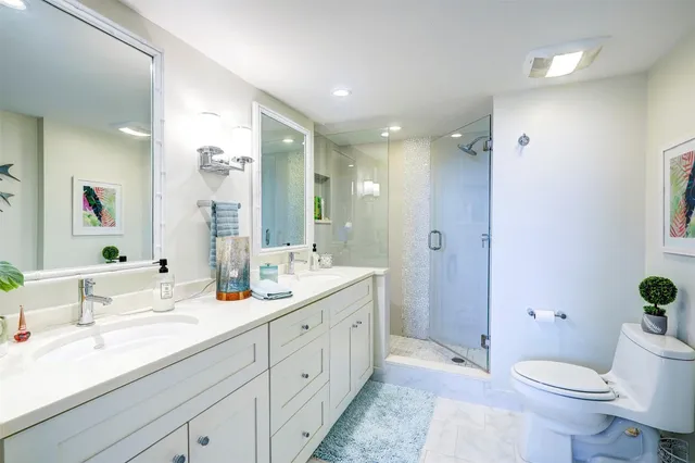 a spacious bathroom with a double vanity sink toilet mirror and shower