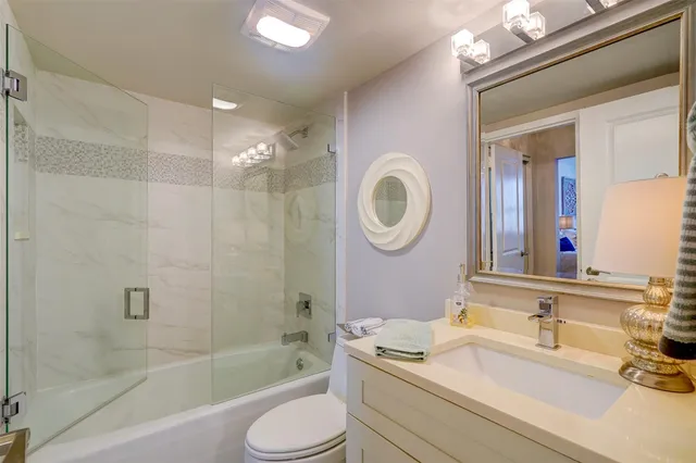 a bathroom with a granite countertop sink mirror toilet and bathtub