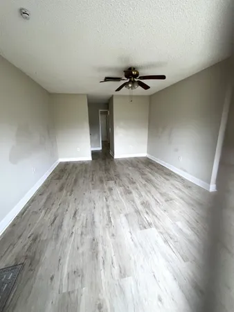 an empty room with wooden floor chandelier and windows