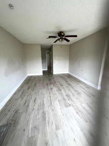 an empty room with wooden floor chandelier and windows