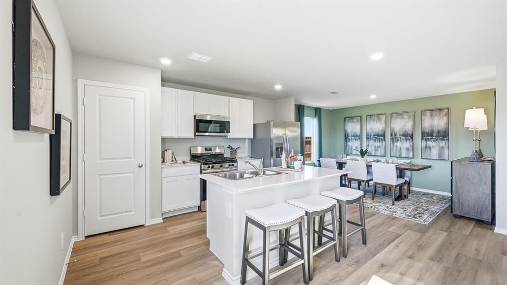 5512 Corduroy Road Krum, TX 76249 - Photo 34 of 38 a kitchen with stainless steel appliances kitchen island granite countertop a refrigerator a stove a sink a dining table and chairs with wooden floor
