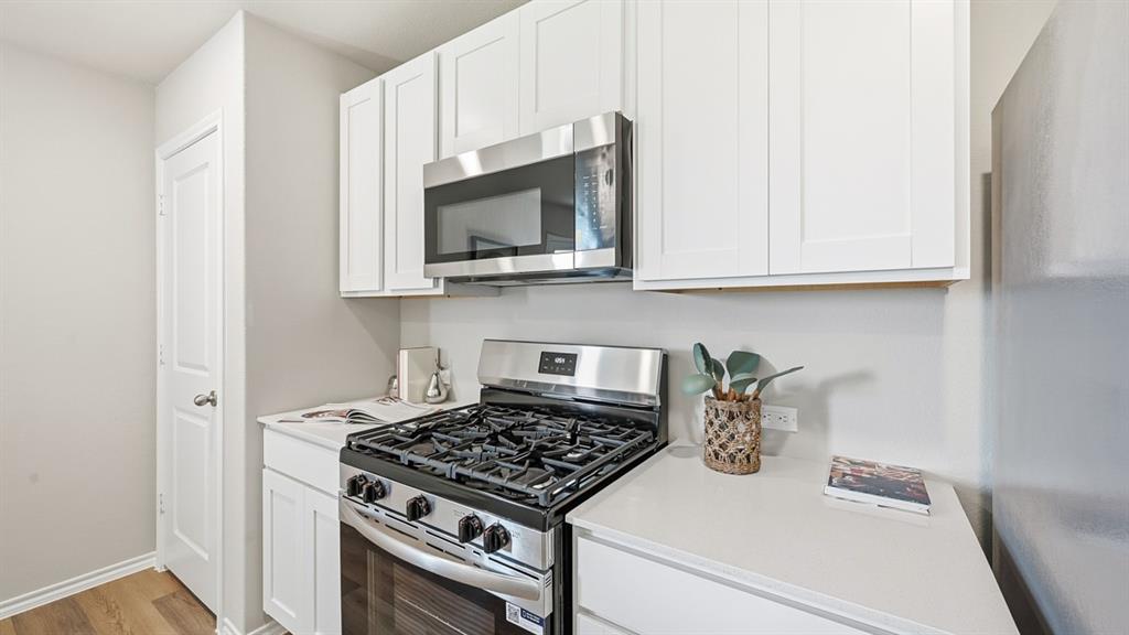 5512 Corduroy Road Krum, TX 76249 - Photo 2 of 38 a kitchen with microwave a stove and cabinets