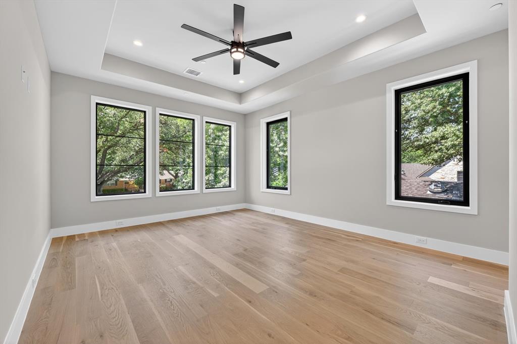 11028 Edgemere Road Dallas, TX 75230 - Photo 31 of 40 Spacious room featuring light wood-finish flooring, a tray ceiling with recessed lighting, and a modern ceiling fan
