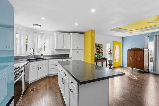 a kitchen with stainless steel appliances granite countertop a sink a stove and wooden floor