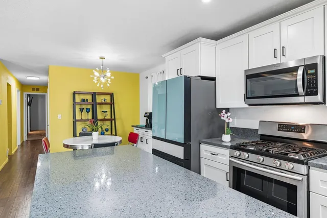 a kitchen with stainless steel appliances kitchen island granite countertop a refrigerator stove and microwave with wooden floor