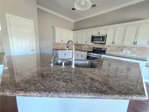a kitchen with a sink a counter top space cabinets and stainless steel appliances