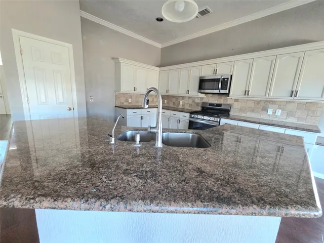 a kitchen with a sink a counter top space cabinets and stainless steel appliances