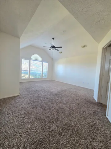 an empty room with windows and ceiling fan