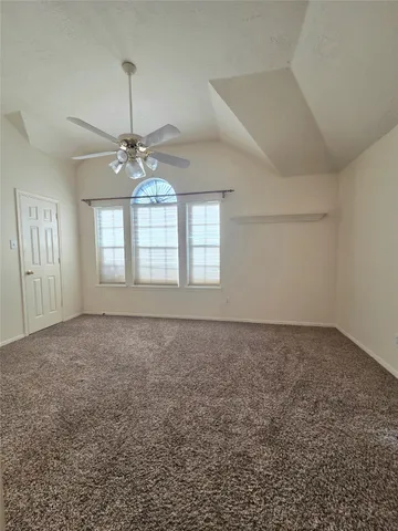 an empty room with a chandelier fan and windows
