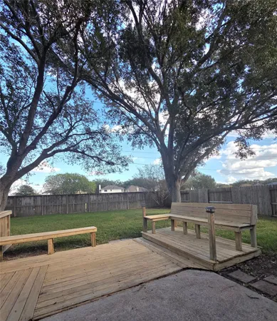 a view of backyard with wooden fence and a large tree