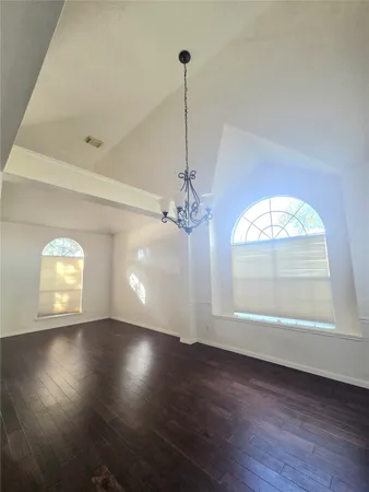 an empty room with wooden floor cabinet and windows