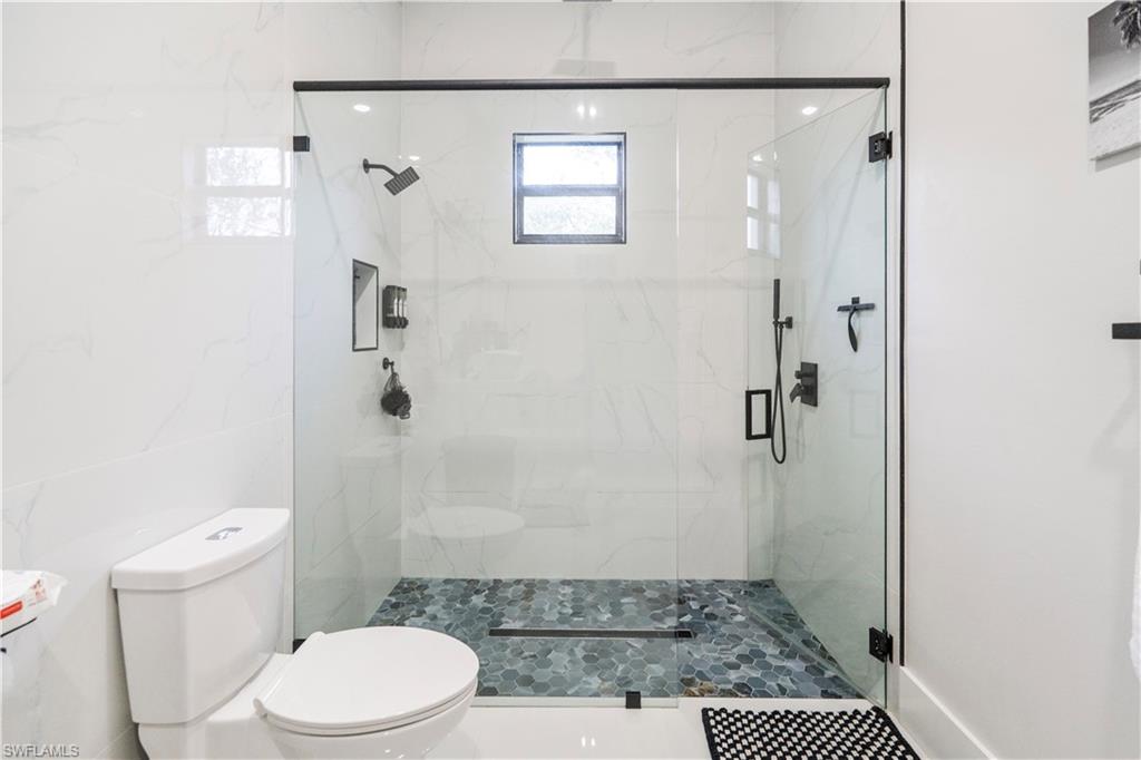 2313 6th Avenue Southeast Naples, FL 34117 - Photo 18 of 36 a bathroom with a granite countertop toilet a sink a shower and a mirror