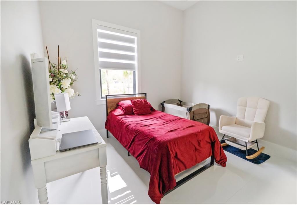 2313 6th Avenue Southeast Naples, FL 34117 - Photo 28 of 36 a bedroom with a bed table chair and a window