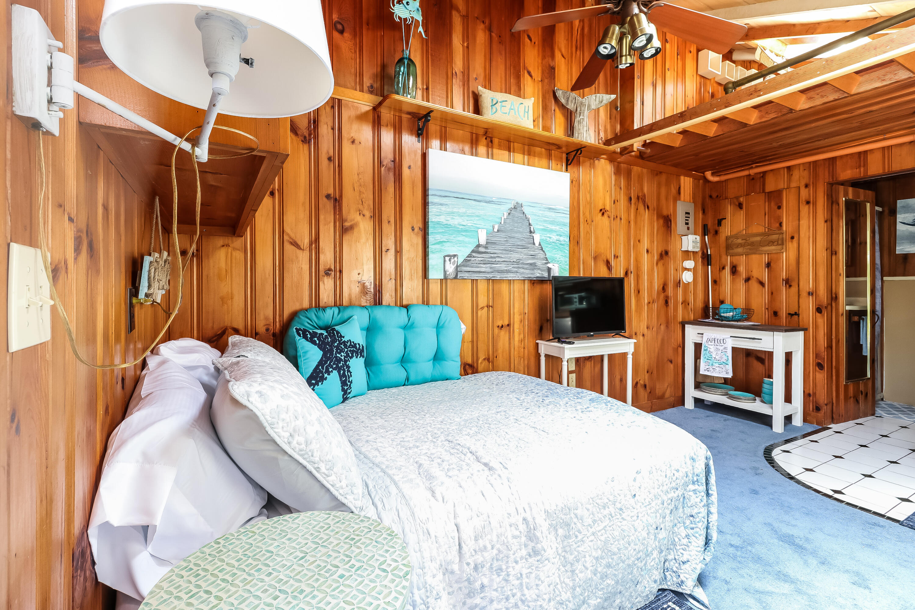 82 Shore Road, Unit 7 Truro, MA 02666 - Photo 3 of 13 a bedroom with a bed a couch and a chandelier