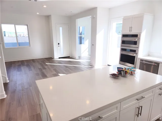 a large kitchen with a center island wooden floor stainless steel appliances and cabinets
