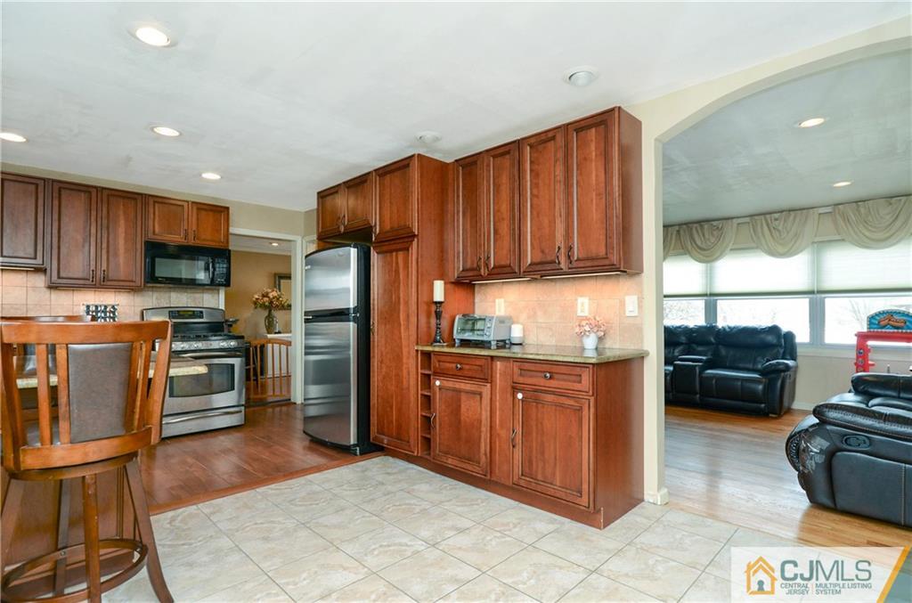 19 Rutgers Road Old Bridge, NJ 08859 - Photo 4 of 25 a kitchen with granite countertop wooden cabinets a stove top oven a refrigerator and a sink