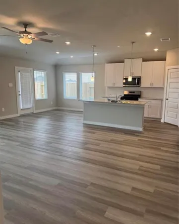 a view of kitchen with kitchen island wooden floors appliances and cabinets
