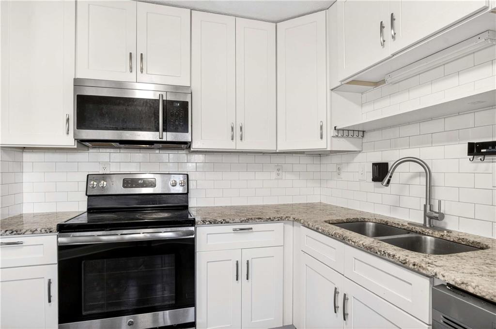 808 Emerald Chase Powder Springs, GA 30127 - Photo 10 of 32 a kitchen with granite countertop white cabinets stainless steel appliances and a sink