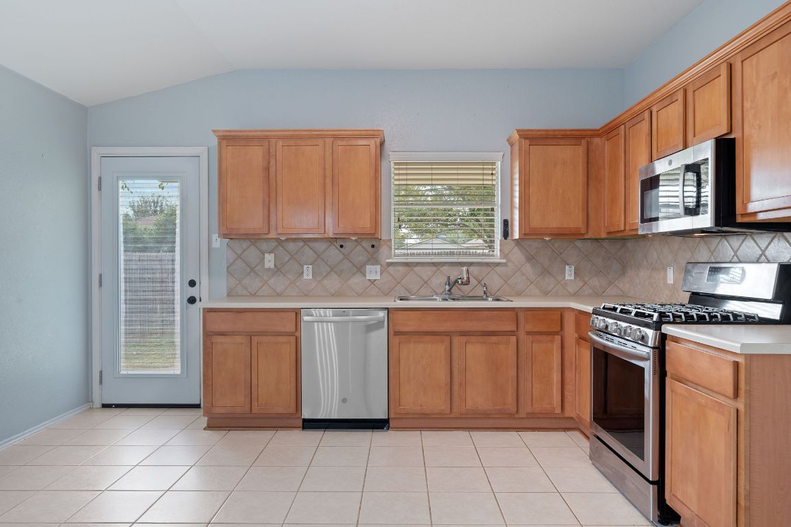 2361 Pearson Way Round Rock, TX 78665 - Photo 6 of 32 a kitchen with stainless steel appliances granite countertop a stove a sink and a microwave