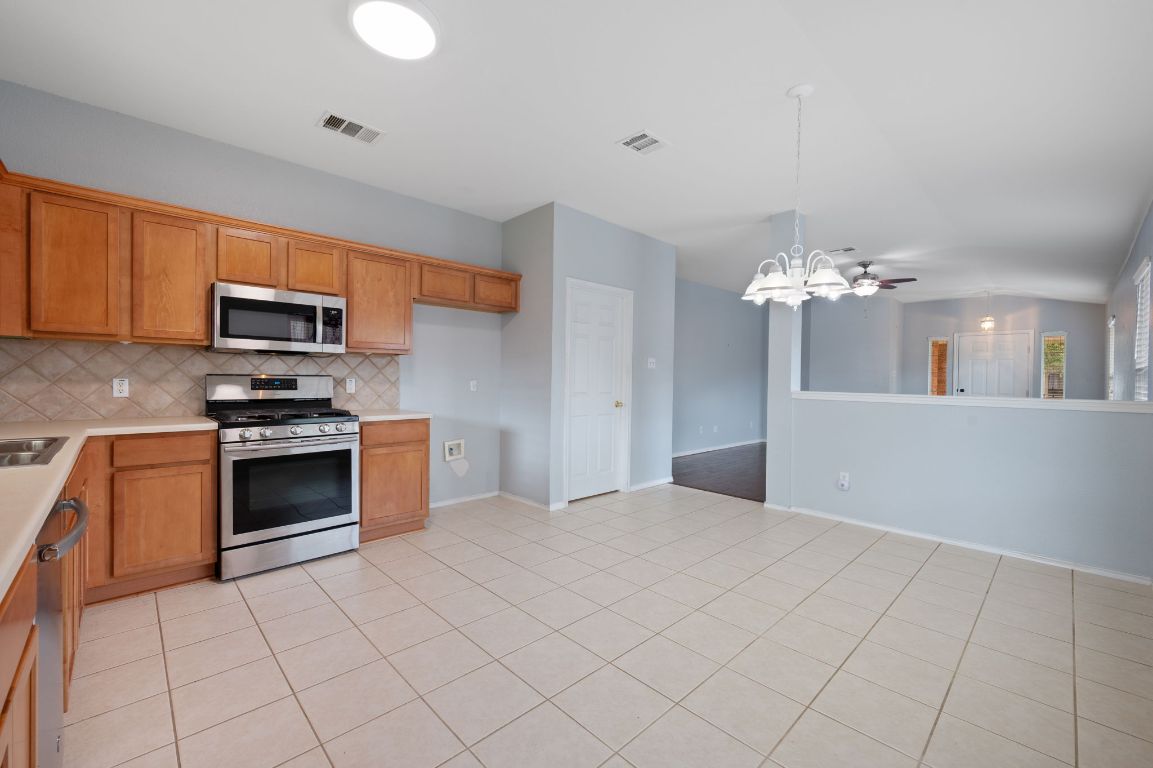 2361 Pearson Way Round Rock, TX 78665 - Photo 7 of 32 a kitchen with granite countertop a stove top oven a sink dishwasher and a refrigerator with wooden floor