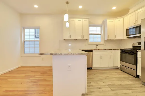 a kitchen with stainless steel appliances granite countertop a stove a sink and white cabinets