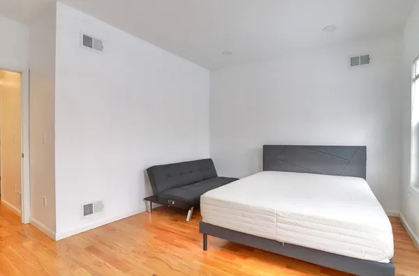 a room with a bed and a chair with the wooden floor