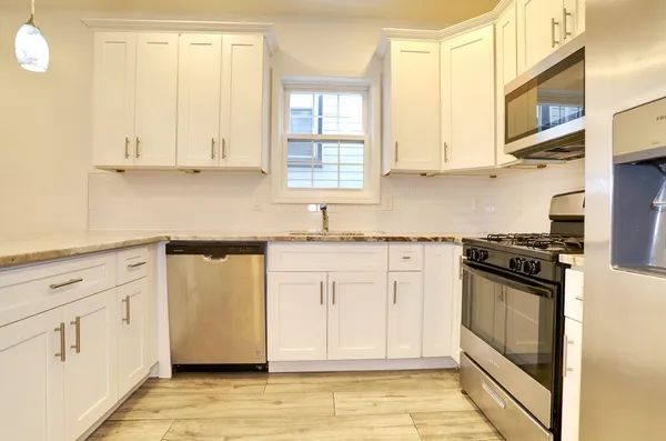 a kitchen with stainless steel appliances granite countertop a stove a sink and white cabinets