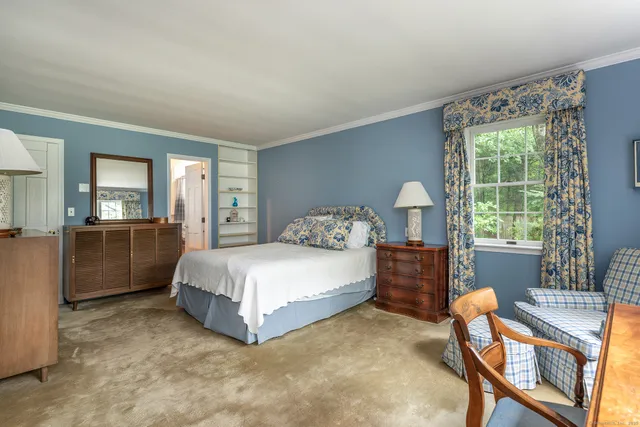 a spacious bedroom with a bed and a dresser next to a window