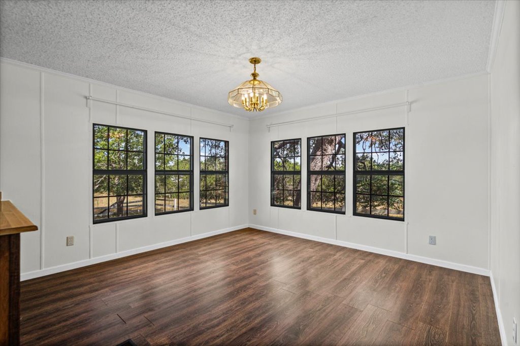 13501 Nutty Brown Road, Unit B Austin, TX 78737 - Photo 14 of 29 A well-lit room with rich hardwood flooring and a classic chandelier, offering serene views through multiple grid-pattern windows.