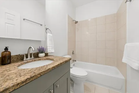 a bathroom with a granite countertop sink a toilet and bathtub
