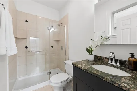 a bathroom with a granite countertop sink a toilet and shower