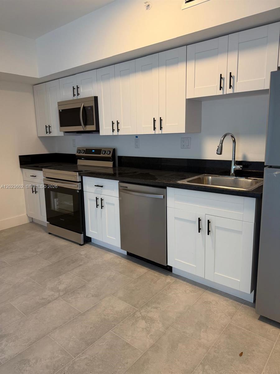 147 Northwest 59th Street, Unit 306 Miami, FL 33127 - Photo 2 of 17 a kitchen with granite countertop a sink a stove and cabinets