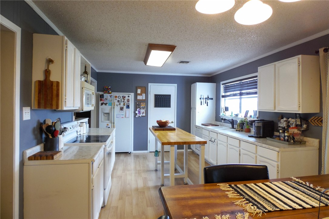 3010 North Interstate 37 Access Three Rivers, TX 78071 - Photo 27 of 29 a kitchen with stainless steel appliances kitchen island granite countertop a refrigerator a sink dishwasher a dining table and chairs with wooden floor