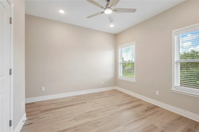 an empty room with wooden floor and ceiling fan