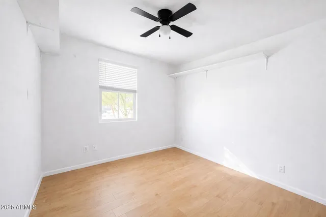 an empty room with a window and a ceiling fan