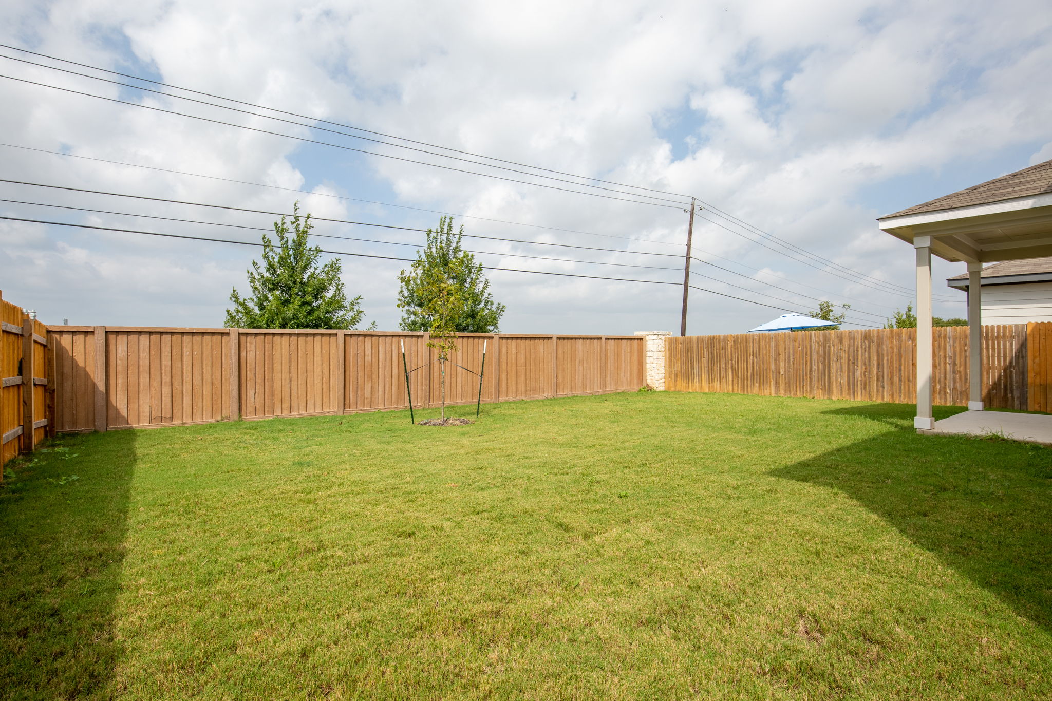 1624 Caballo Blanco Road Austin, TX 78725 - Photo 24 of 27 An expansive green lawn is fully enclosed by a sturdy wooden privacy fence.