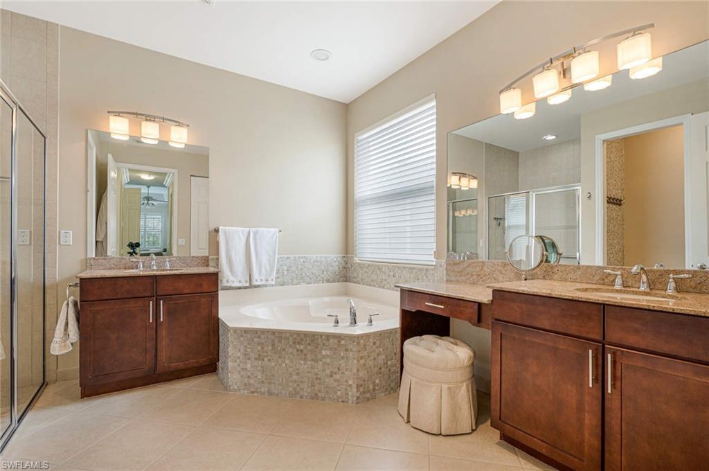 6549 Marbella Drive Naples, FL 34105 - Photo 13 of 28 a bathroom with a tub double vanity sink and a large mirror