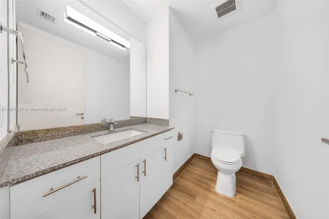 a bathroom with a granite countertop sink a toilet and a mirror