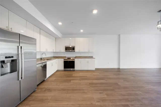 a large kitchen with stainless steel appliances granite countertop a stove a sink and a refrigerator