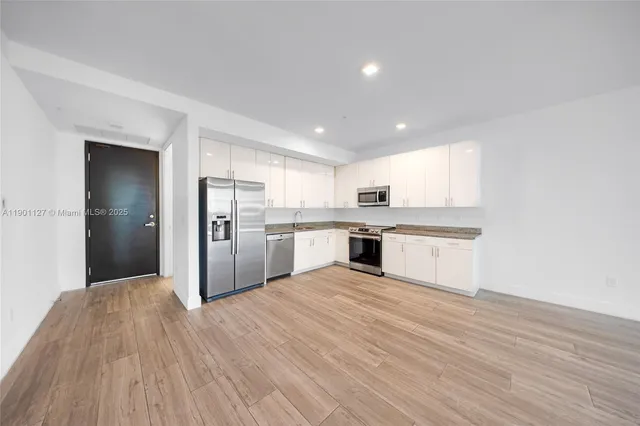 a large kitchen with a refrigerator and white cabinets