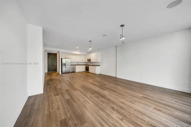 a view of kitchen with refrigerator stove and wooden floor