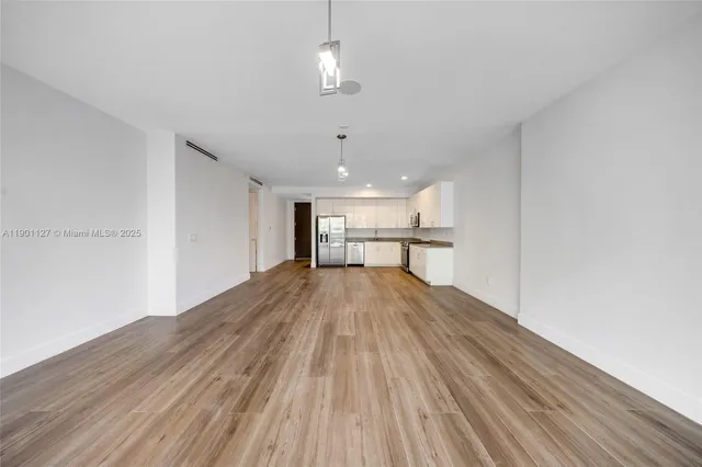 a view of empty room with wooden floor and window