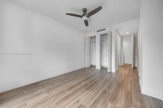 a view of empty room with wooden floor and ceiling fan