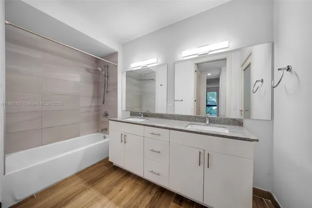 a bathroom with a granite countertop sink mirror and a bathtub