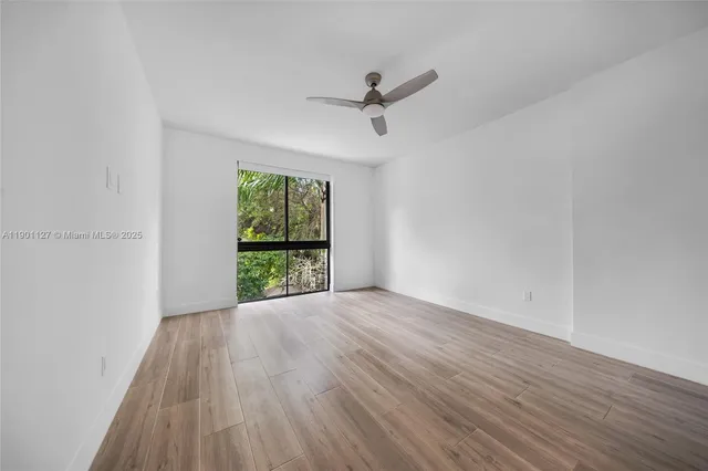 a view of an empty room with wooden floor and a window